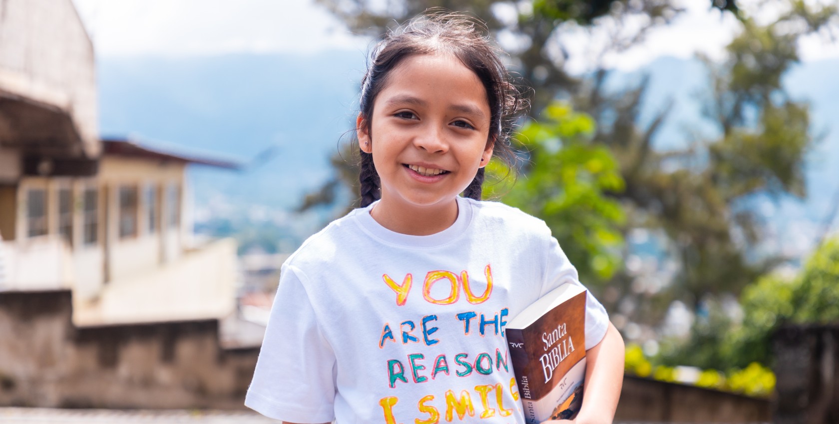 A girl holding a bible smiling